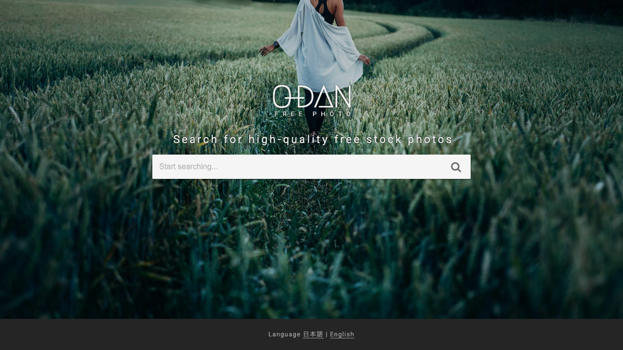 The O-DAN screen. The O-DAN logo over a large photo of a field, a “Search for high-quality free stock photos” heading with a single search box, and a language switcher at the bottom